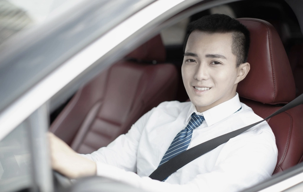 Smiling young business man driving a car
