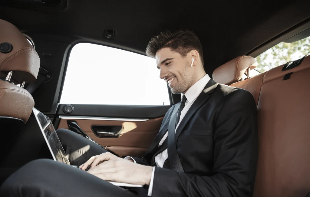 businessman in an airport car service vehicle working on the go with laptop