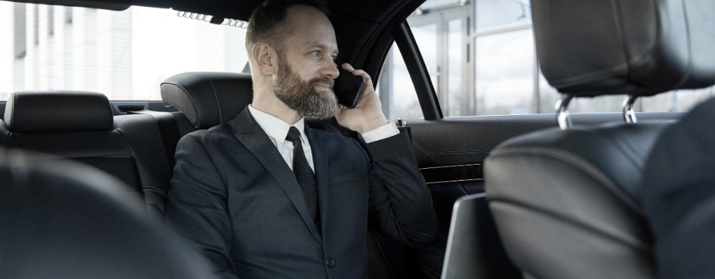 businessman on phone enjoying in-car wifi during an airport limousine service