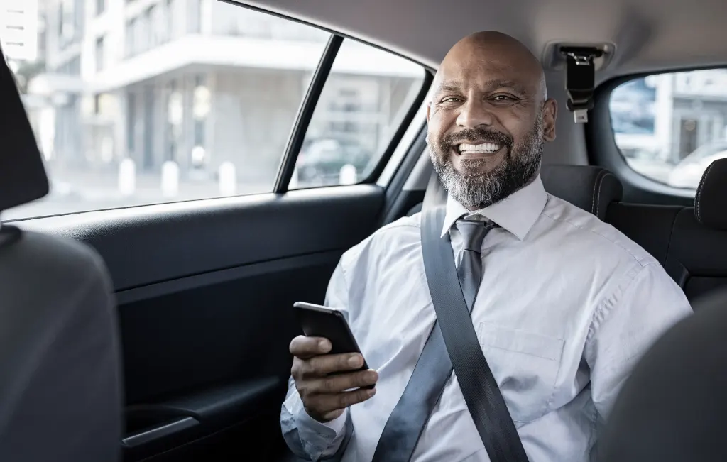 businessman with his phone inside a hired airport car service