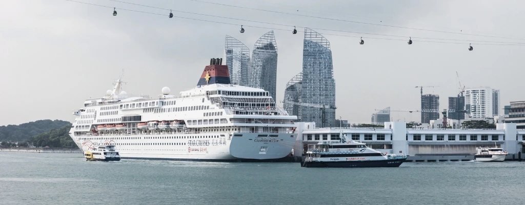 cruise ship docked at a modern harbor with high-rise buildings in the background